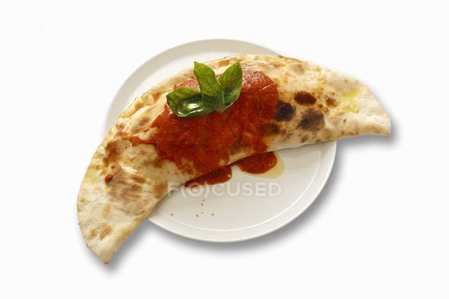 Closeup view of Calzone with tomato sauce and basil — Stock Photo