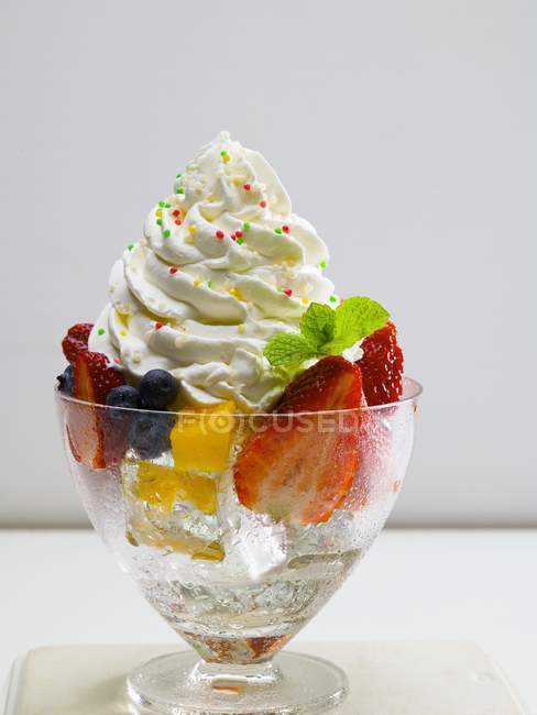 Primo piano vista di frutta mista su cubetti di ghiaccio con panna montata — Foto stock