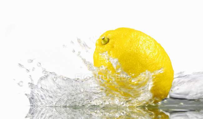 Limón con agua salpicada - foto de stock