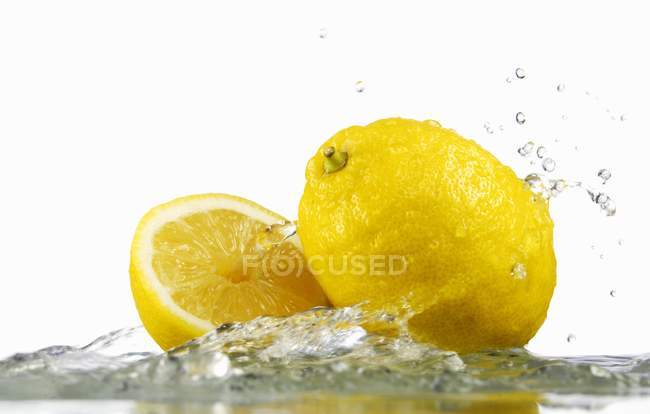 Limones con agua salpicada - foto de stock