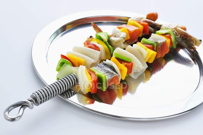 Frutos do mar crus e kebabs vegetais em placa de metal — Fotografia de Stock