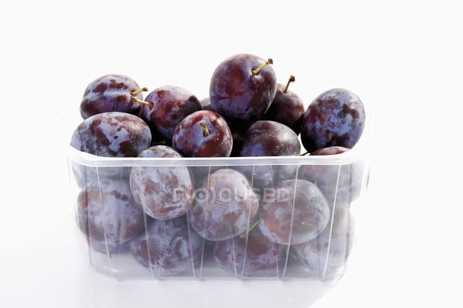 Fresh plums in plastic container — Stock Photo