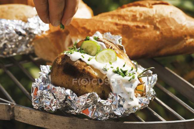 Main humaine saupoudrer de pommes de terre avec de la ciboulette — Photo de stock