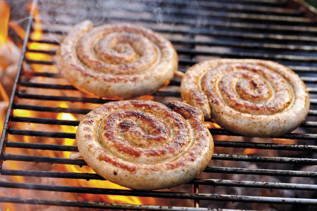 Coiled sausages on barbecue rack — Stock Photo