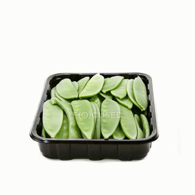 Mangetout in a plastic tray on white background — Stock Photo