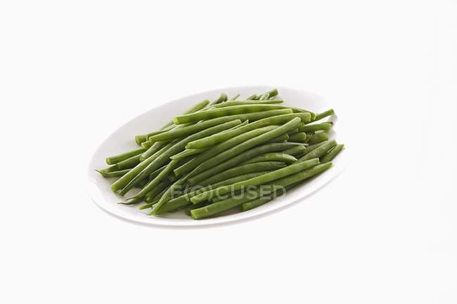 Blanchierte grüne Bohnen auf Teller auf weißem Hintergrund — Stockfoto