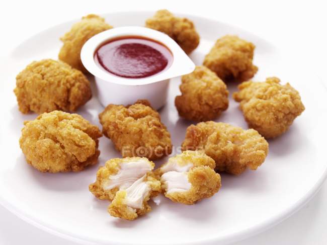 Primo piano vista di pepite di pollo con tuffo sul piatto bianco — Foto stock