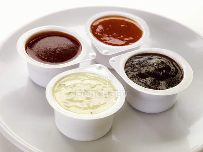 Elevated view of four different dips in plastic pots — Stock Photo