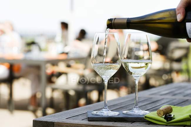 Наливание белого вина в бокалы — стоковое фото