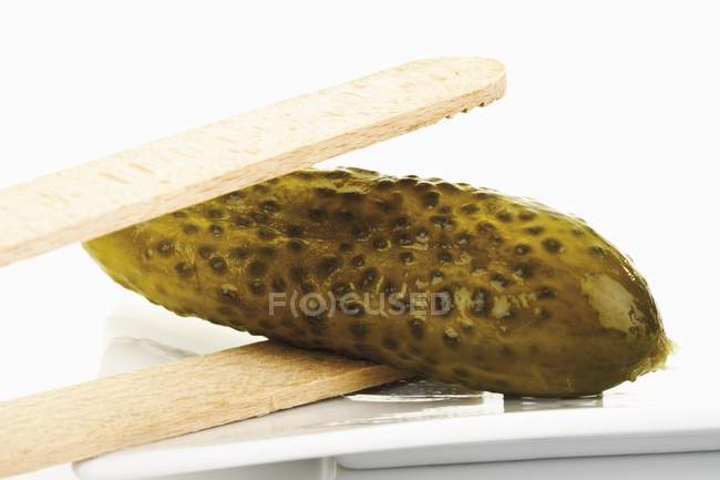 Pickled gherkin in wooden tongs — Stock Photo