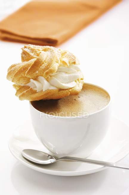 Profiterole on cup of coffee — Stock Photo