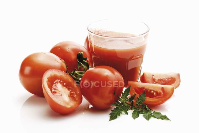 Glass of tomato juice with Roma tomatoes — Stock Photo