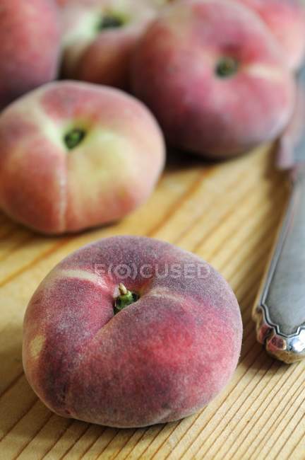 Плоскі персики і ніж — стокове фото