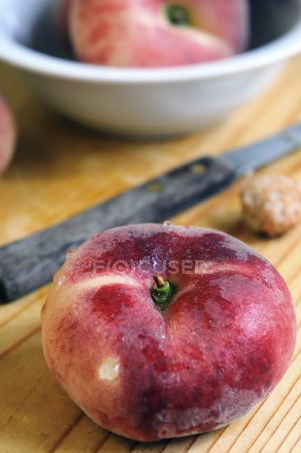 Плоские персики и нож — стоковое фото