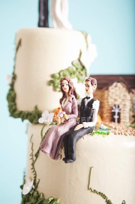 Closeup view of wedding cake with figures of sitting bride and groom — Stock Photo