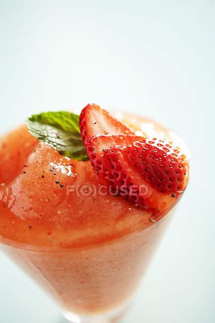 Nahaufnahme von Fruchtpüree mit Erdbeerscheiben und grünem Blatt im Glas — Stockfoto