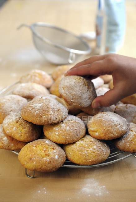 A little boys hand taking an Italian pumpkin biscuit on plate — Stock Photo