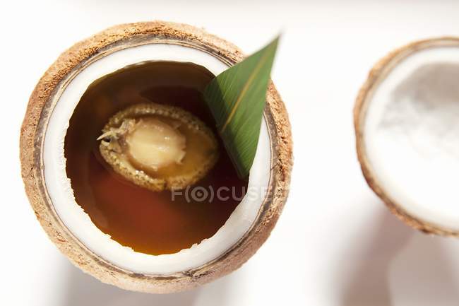 Gros plan vue du dessus de la soupe de poulet dans la noix de coco à l'ormeau — Photo de stock
