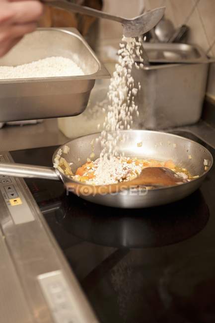 Chef vertiendo arroz en la sartén - foto de stock