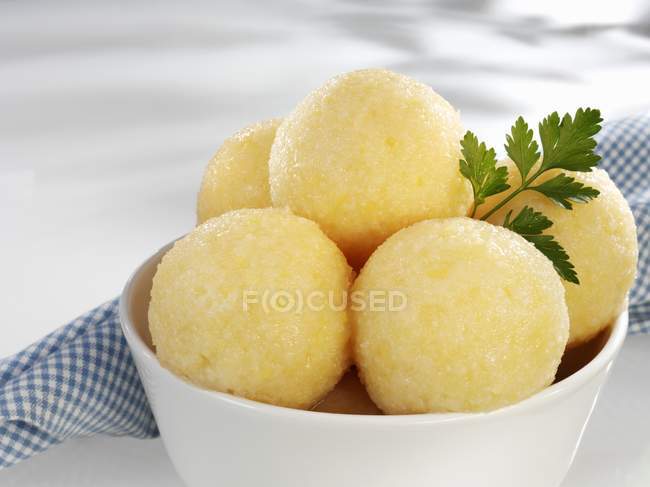 Several potato dumplings in bowl on white surface  with tea-towel — Stock Photo