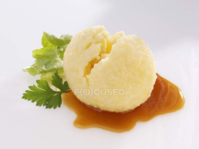 Potato dumpling with gravy and parsley over white surface — Stock Photo