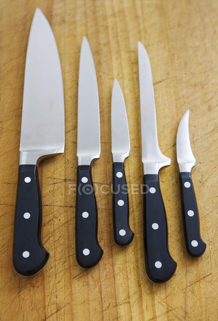 Vista de cerca de cuchillos de cocina surtidos en una fila - foto de stock