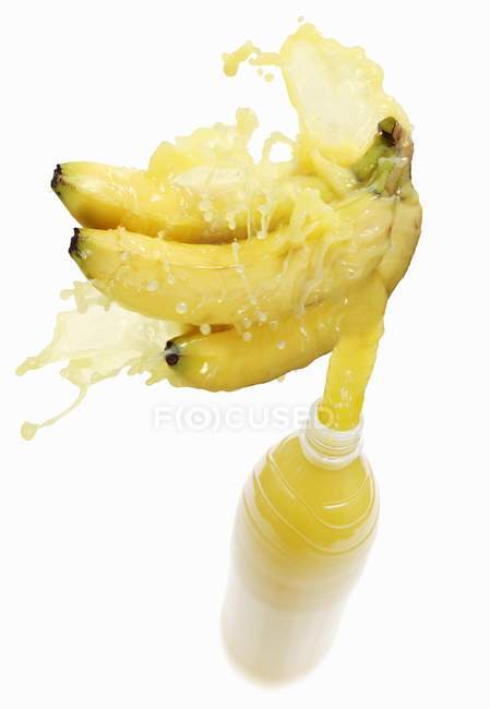 Banana juice splashing out of bottle — Stock Photo
