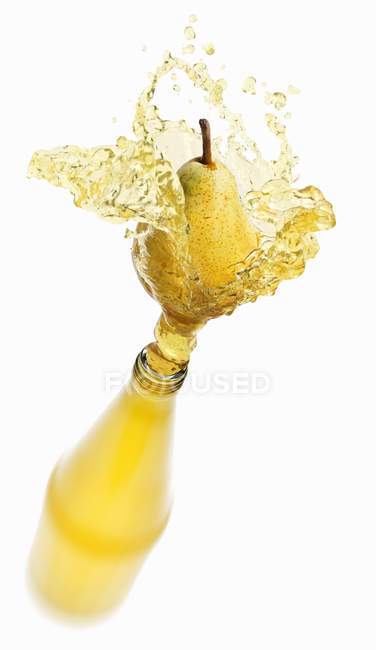 Pear juice splashing out of bottle — Stock Photo