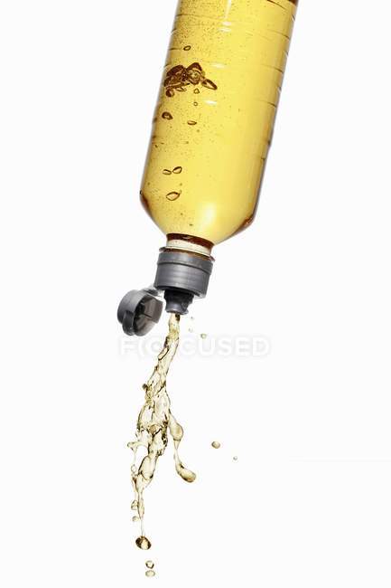 Vista de perto da bebida de energia amarela salpicando para fora da garrafa — Fotografia de Stock