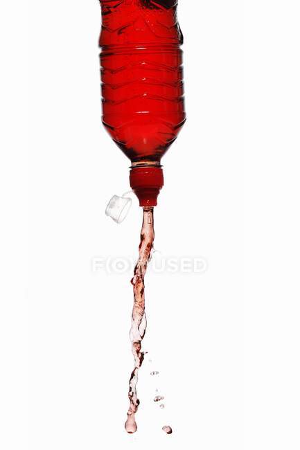 Closeup view of red energy drink squirting out of bottle — Stock Photo