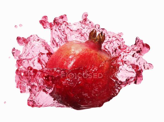 Pomegranate with splashing pomegranate juice — Stock Photo