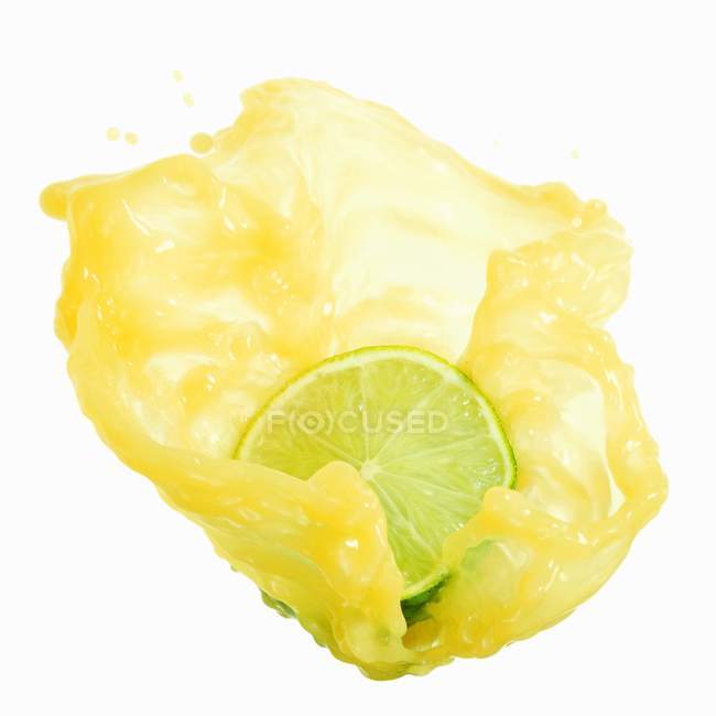 Half a lime with splashing lime juice — Stock Photo