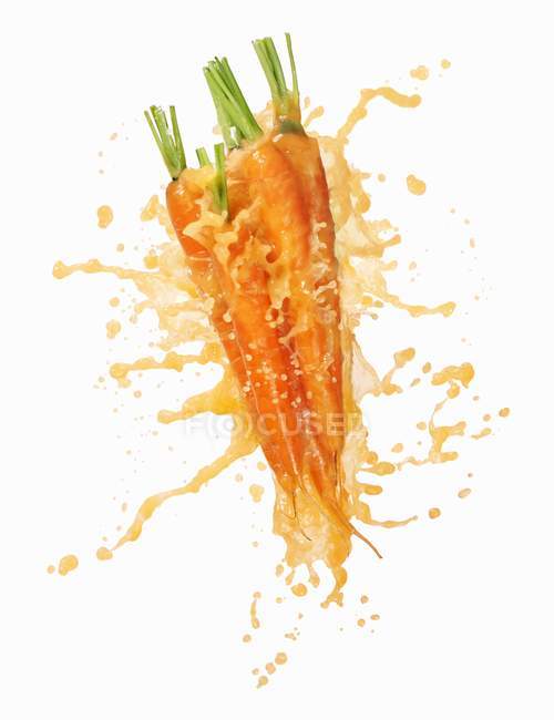 Zanahorias con jugo de zanahoria salpicante - foto de stock