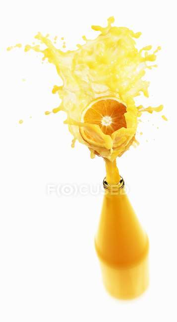Sumo de laranja salpicando para fora da garrafa — Fotografia de Stock