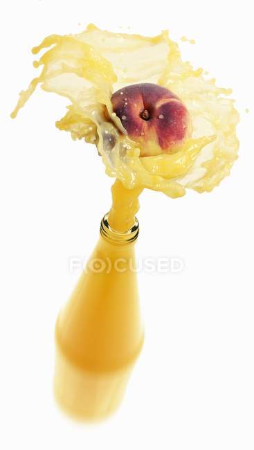 Pfirsichsaft spritzt aus Flasche — Stockfoto