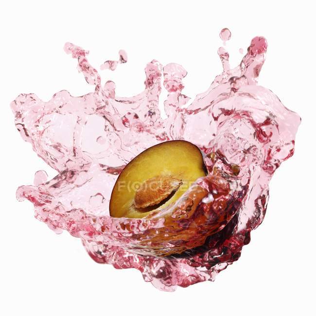 Demi-prune avec éclaboussures de jus de prune — Photo de stock