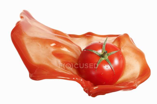 Tomate en salpicadura de ketchup - foto de stock