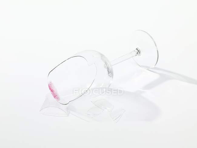 Vista close-up de um copo de vinho quebrado na superfície branca — Fotografia de Stock