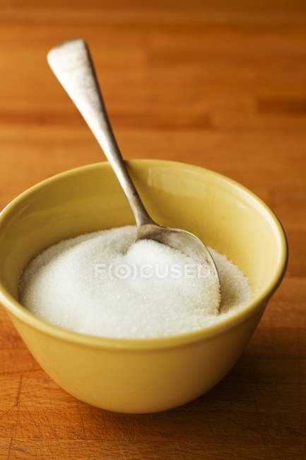 Vista close-up de açúcar branco com colher em tigela na superfície de madeira — Fotografia de Stock