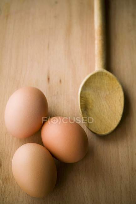 Huevos pardos y cuchara de madera - foto de stock