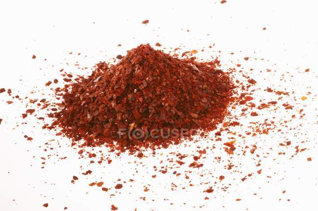 Closeup view of coarsely ground Chilli powder heap on white surface — Stock Photo