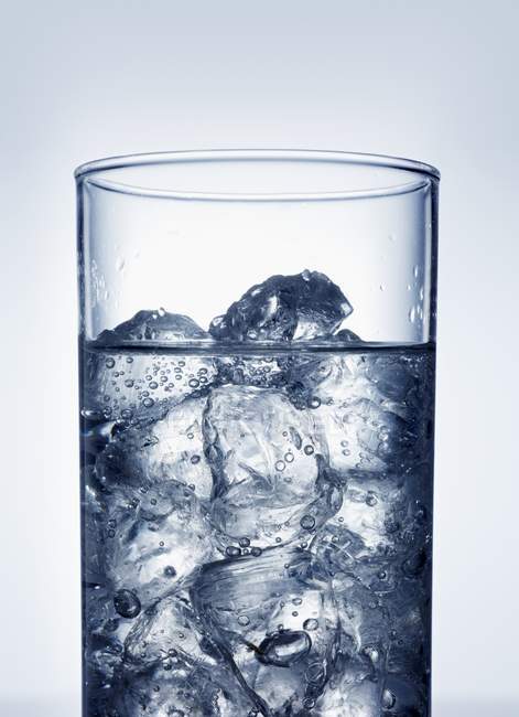 Cubitos de hielo en un vaso de agua - foto de stock