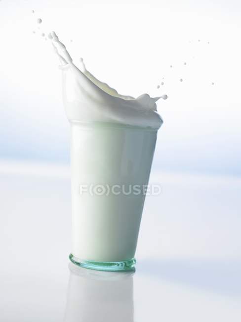 Glass of milk splashing — Stock Photo