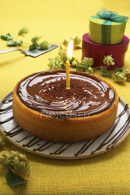 Cake with chocolate icing and candle — Stock Photo
