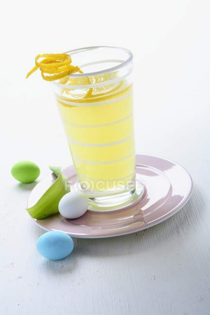 Лимонний напій у склянці над тарілкою — стокове фото