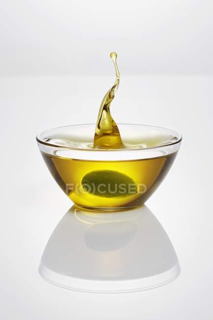 Olive falling into glass dish — Stock Photo