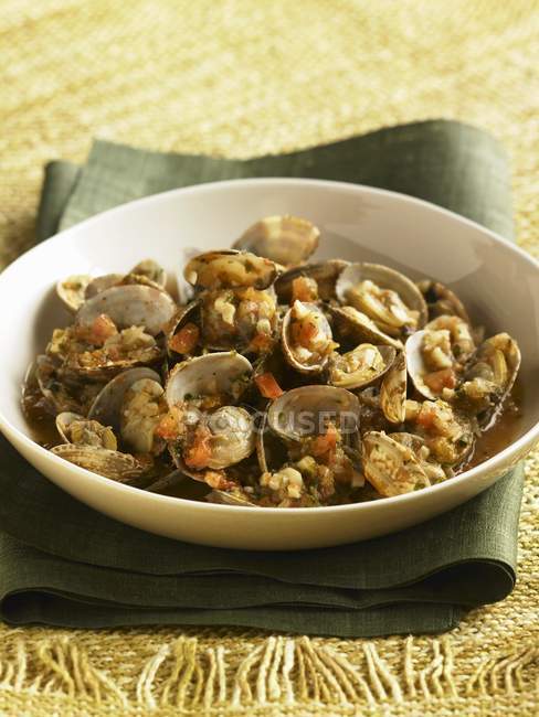 Clams with Tomatoes in Broth on white plate over towel — Stock Photo