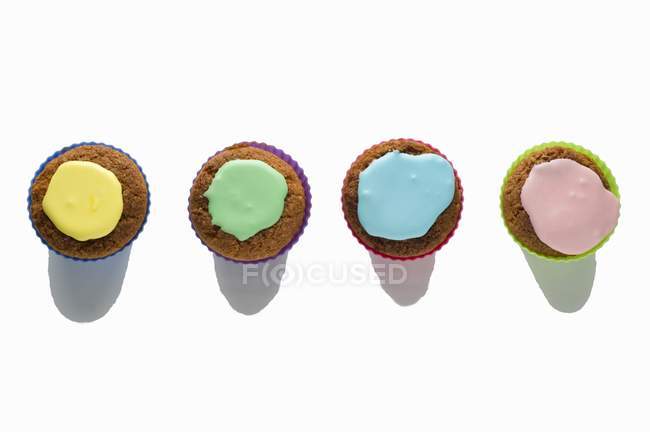 Four cupcakes with colorful icing — Stock Photo