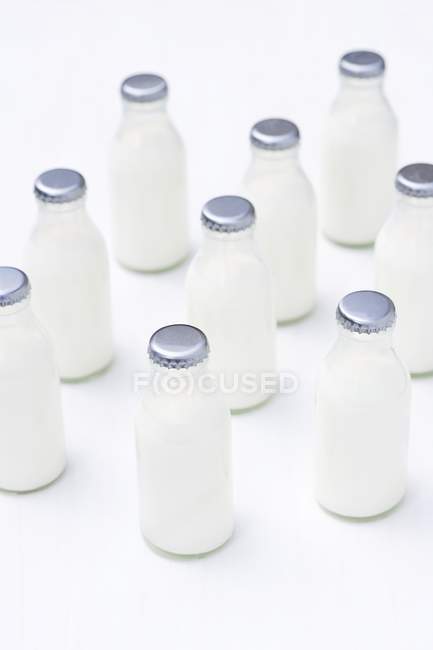 Vista elevada de pequeñas botellas de crema en la superficie blanca - foto de stock