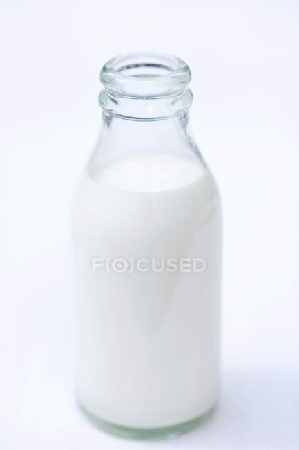 Nahaufnahme einer geöffneten Flasche Sahne auf weißer Oberfläche — Stockfoto